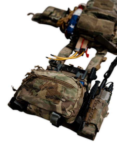 A tactical vest and hip pouch system in camouflage fabric, shown against a plain white background. The gear includes multiple pouches, straps, and attached accessories.