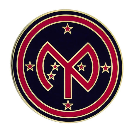 A circular emblem or patch featuring a navy blue background with a large red stylized monogram in the center, surrounded by a red ring and bordered by gold lines, with small red stars around the design.