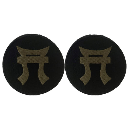 Two black round patches with a gold symbol on a white background