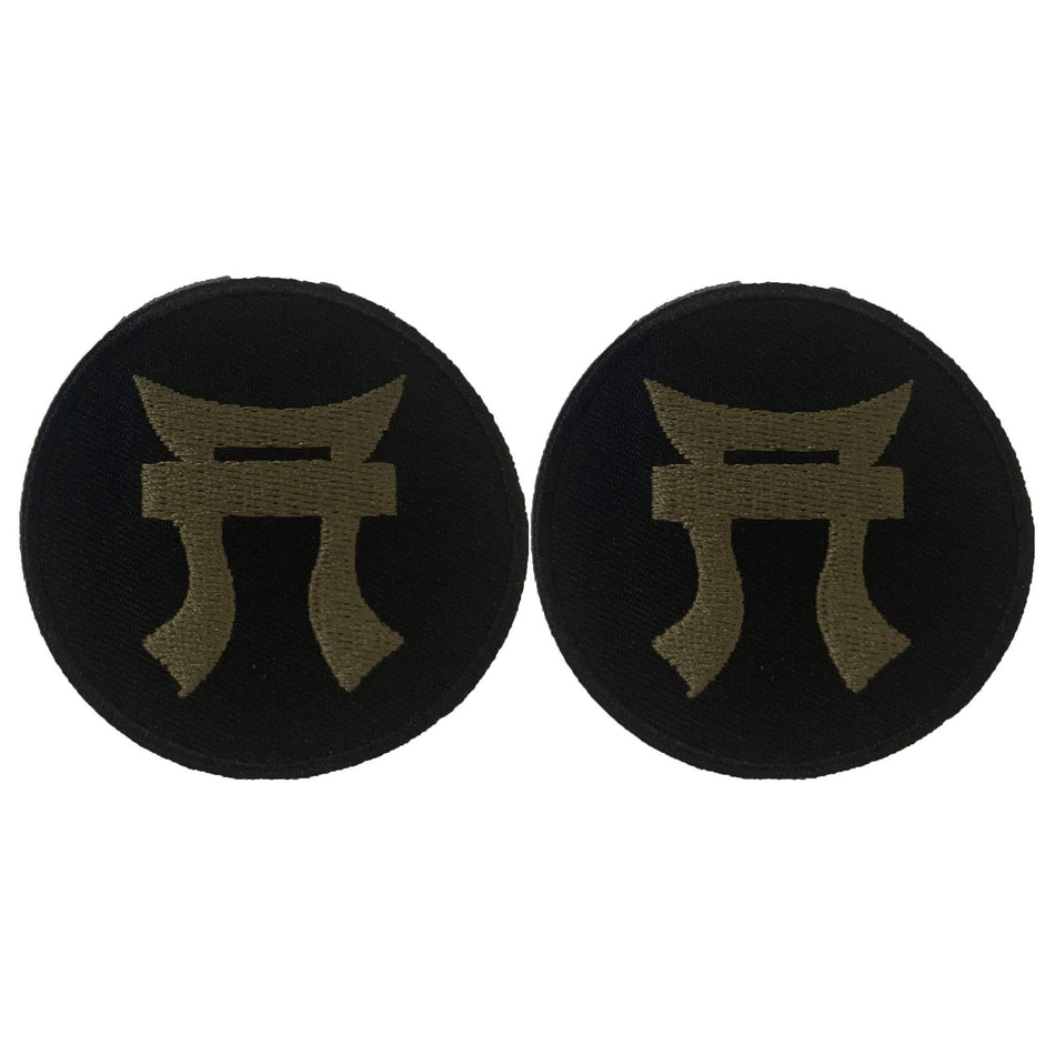 Two black round patches with a gold symbol on a white background