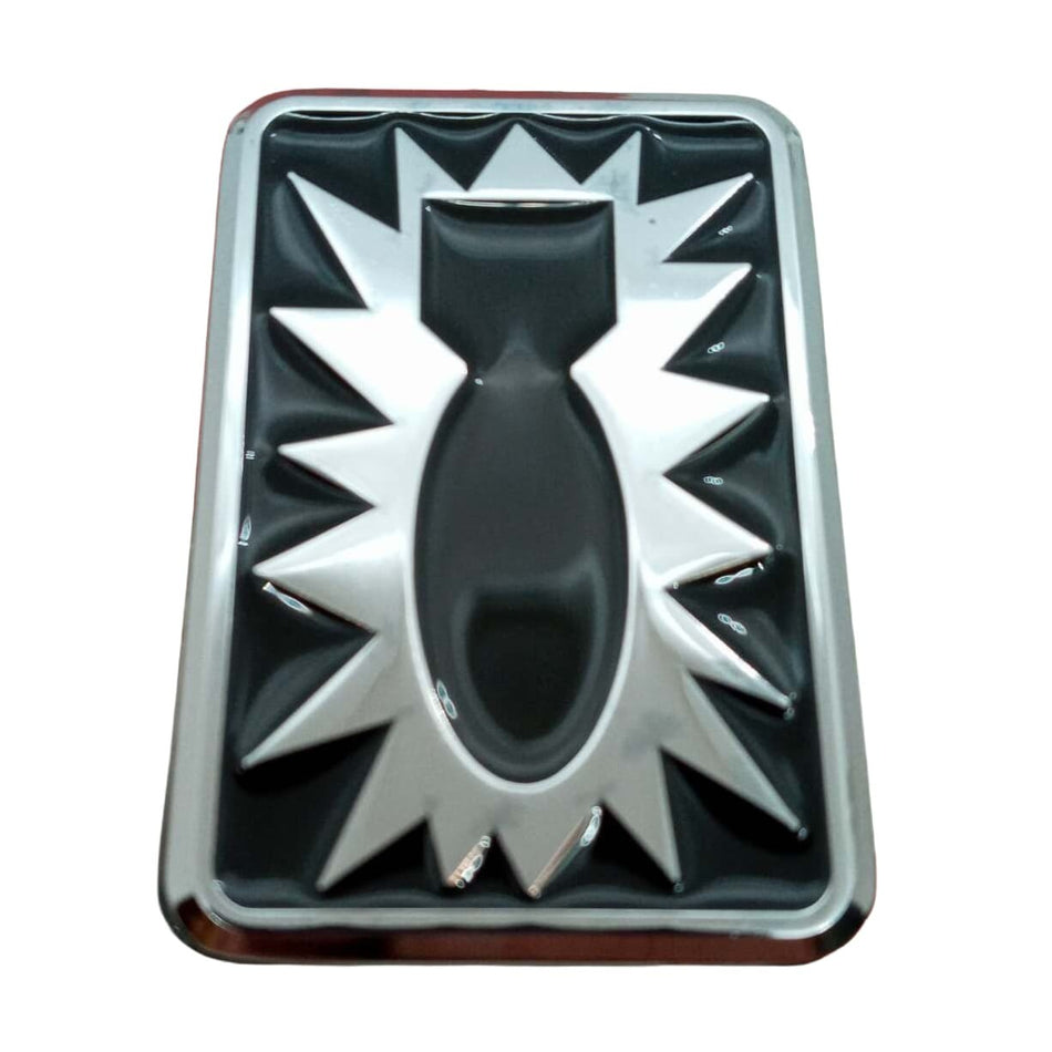 A rectangular chrome emblem or badge featuring a stylized fish design with a black center and silver starburst rays, shown on a plain white background.