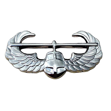 A silver metallic military insignia pin featuring a central helmet beneath a horizontal bar with curved wing-like extensions on each side, shown on a plain white background.