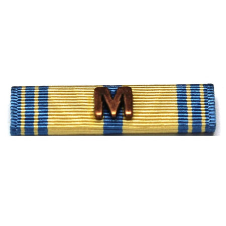 A military ribbon bar with a gold and blue striped pattern and a central bronze-colored letter 'M'.