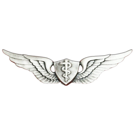 A silver-toned military-style winged insignia with a central shield and caduceus symbol, isolated on a white background.