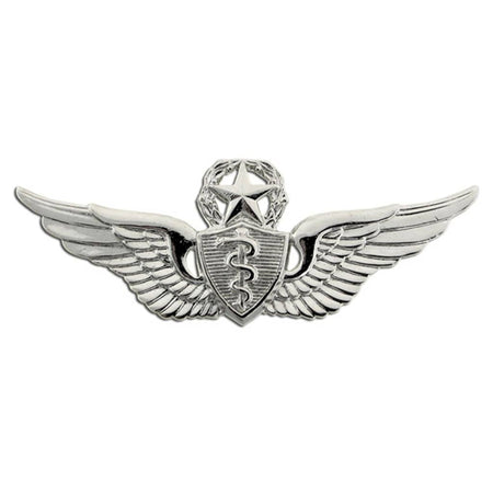 A silver-colored metal military insignia featuring wings, a star, a shield with a caduceus symbol, and a wreath on a plain white background.