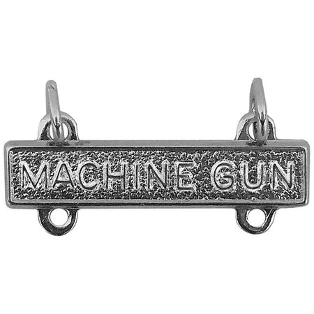 A silver-toned rectangular metal charm or pendant with the words 'MACHINE GUN' raised across the front, shown on a plain white background.