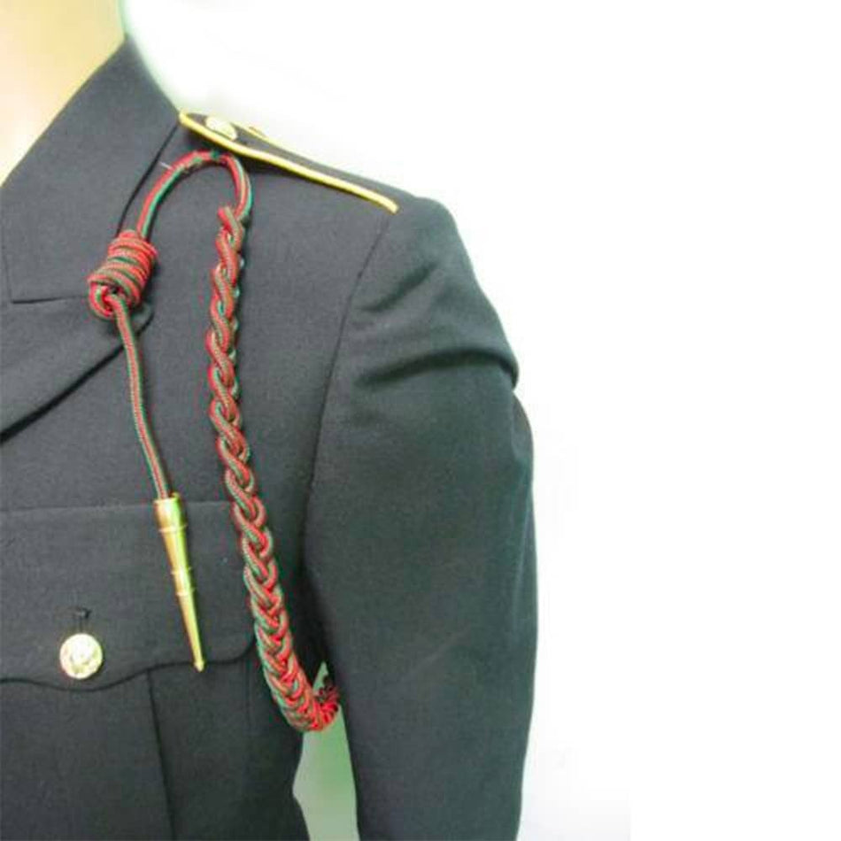 A close-up of a black military-style jacket on a mannequin, featuring a red and green braided cord accessory draped over the shoulder with gold-toned metal accents.