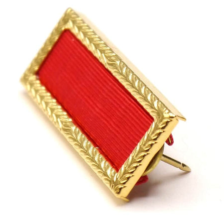 Gold-framed badge with red ribbon on a white background