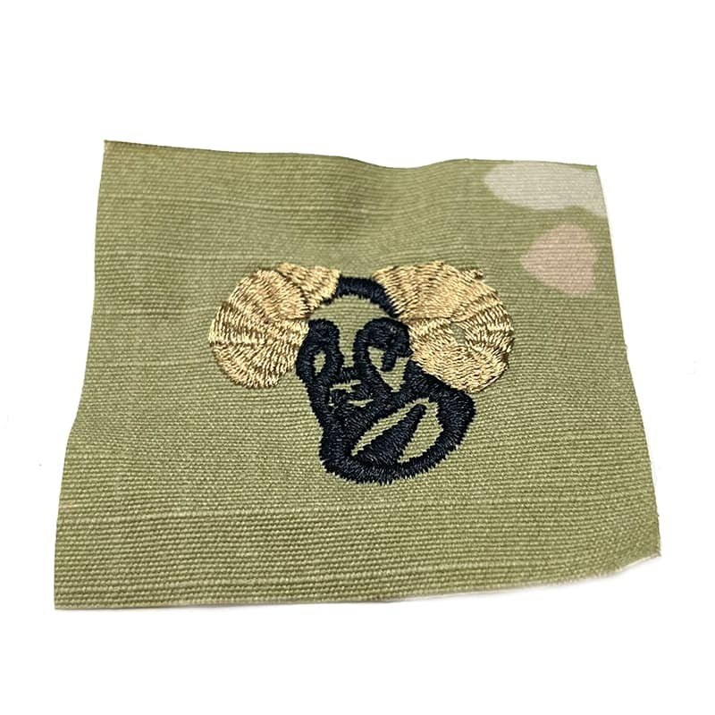 Embroidered patch of a face with round ears on a OCP fabric background
