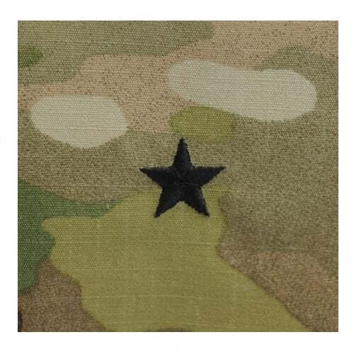 A close-up of a camouflage fabric patch with a black embroidered five-pointed star in the center.