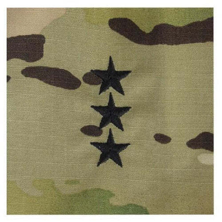 Close-up of a camouflage fabric with three black embroidered stars arranged vertically on the right side.