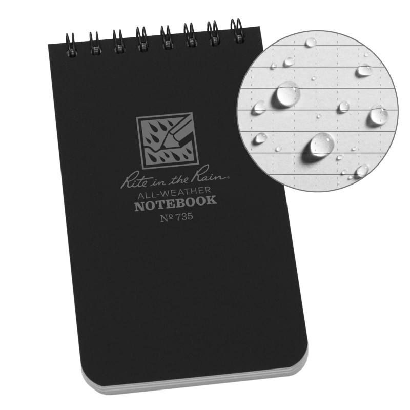 A black hardcover spiral notebook with a circular inset showing water droplets on the lined pages, indicating waterproof quality. The cover features the 'Kite in the Rain' logo and text.