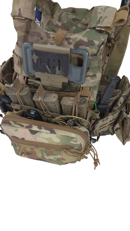 A tactical vest or plate carrier in Multicam camouflage pattern, shown against a plain white background. The vest features multiple pouches, MOLLE webbing, and a gray plastic quick-release buckle on the front.