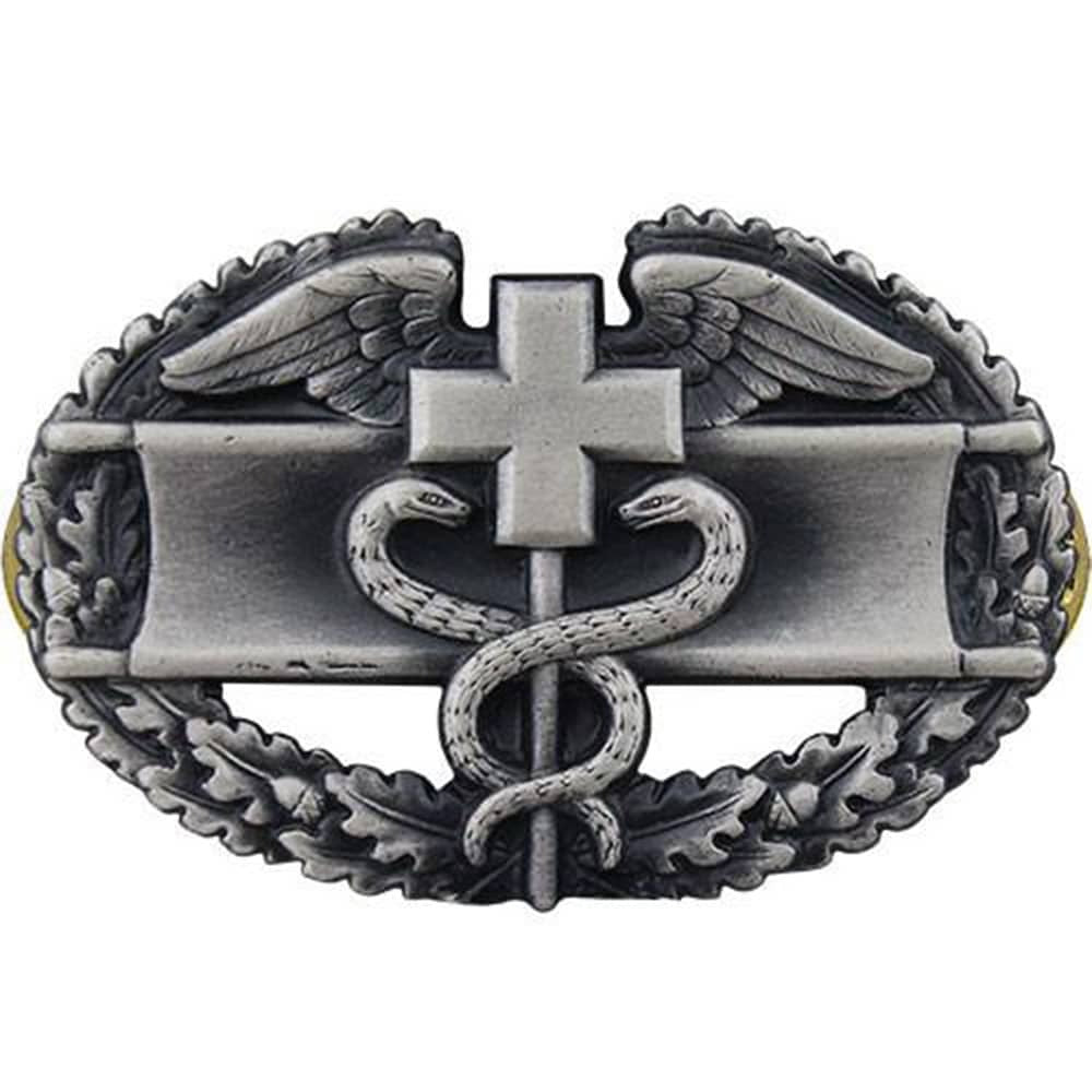 A silver-toned metal belt buckle featuring a medical-themed design with a cross, snake, wings, and laurel wreath on a plain white background.