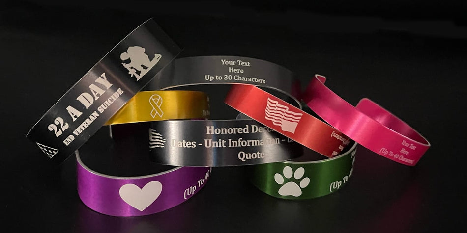 Colorful memorial bracelets with various designs and text on a dark background