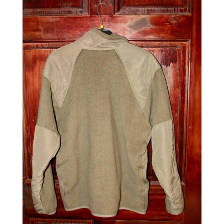 A fleece pullover jacket with a high collar, featuring a solid brown body and contrasting tan shoulder and sleeve panels, hanging on a black hanger against a dark reddish-brown wooden door.