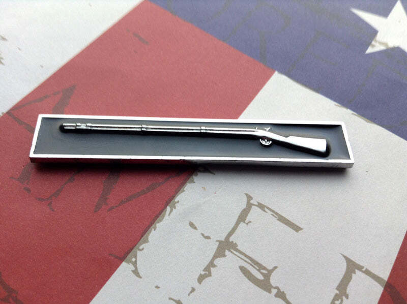 A blue and silver metal car decal representing the Army Expert Infantryman Badge, placed on a red and white surface.