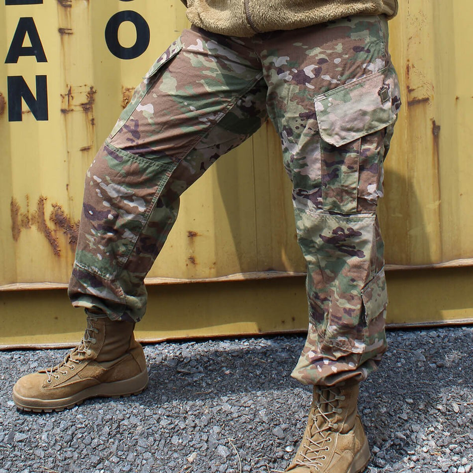 Person wearing OCP pants and boots standing in front of a yellow container with rust.
