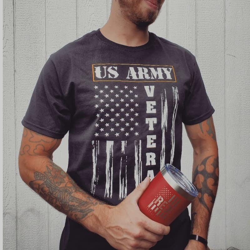 Person wearing a US Army Veteran t-shirt holding a red cup with a logo.