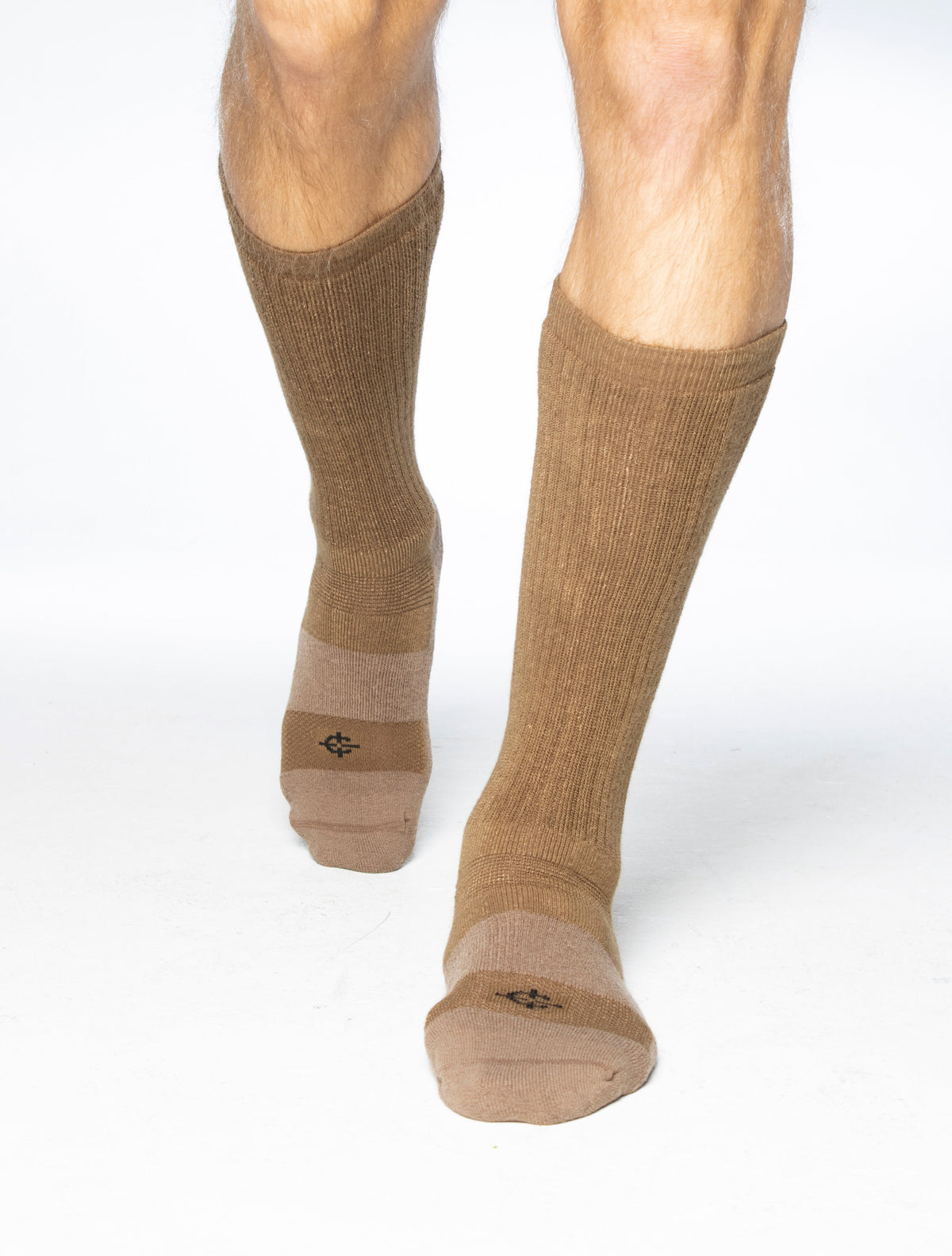 A pair of knee-high ribbed socks in a warm tan-brown color worn on a person's legs, shown against a clean white background.