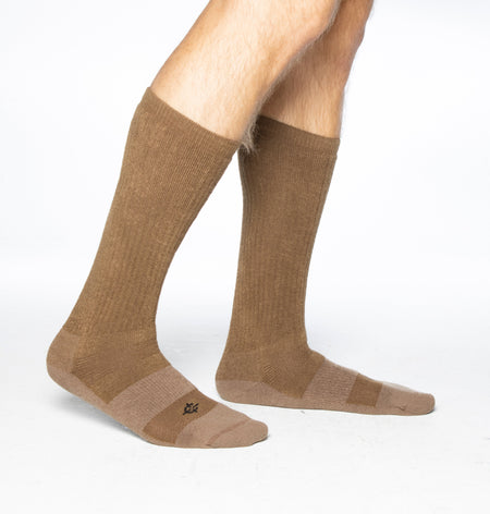 A pair of ribbed knee-high socks in a warm taupe-brown color, shown on a person's feet against a clean white background.