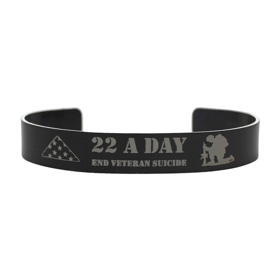 A black metal cuff bracelet with engraved silver-gray text reading '22 A DAY END VETERAN SUICIDE' along with a triangle flag design and kneeling soldier silhouette, shown on a plain white background.