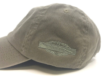 A close-up of a gray fabric baseball cap with a curved brim and an embroidered logo patch on the side, photographed against a white background.