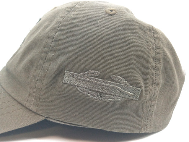 An olive green baseball cap with a tonal embroidered patch on the front, photographed against a white background.