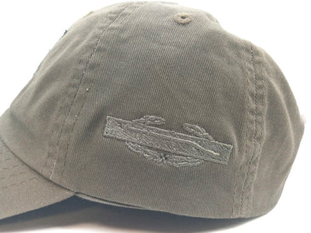 An olive green baseball cap with a tonal embroidered patch on the front, photographed against a white background.