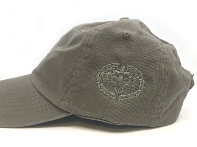 An olive drab baseball cap featuring an embroidered US Navy SEAL Trident insignia on the front, set against a plain white background.