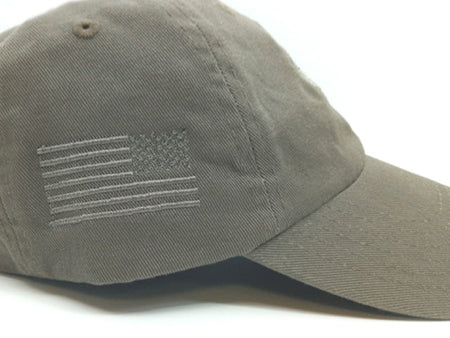 An olive drab baseball cap featuring an embroidered American flag on the side, shown against a plain white background.