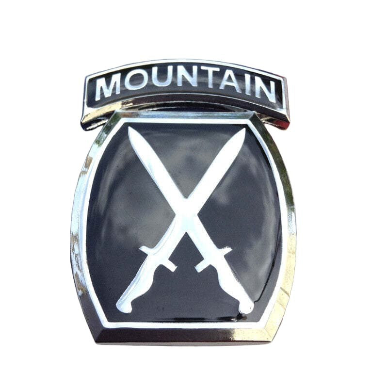 A black and silver car emblem badge featuring the word 'MOUNTAIN' on an arched top bar and two crossed swords on a shield below.