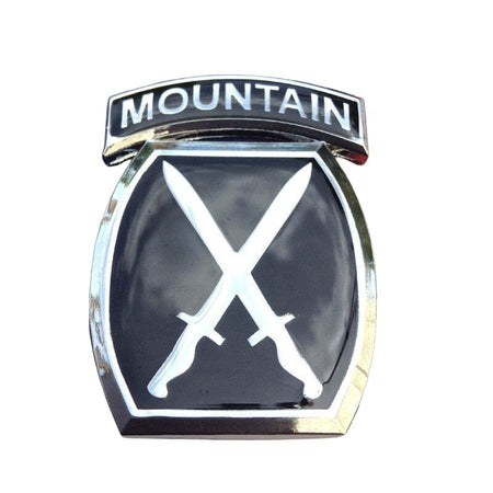 A black and silver car emblem badge featuring the word 'MOUNTAIN' on an arched top bar and two crossed swords on a shield below.