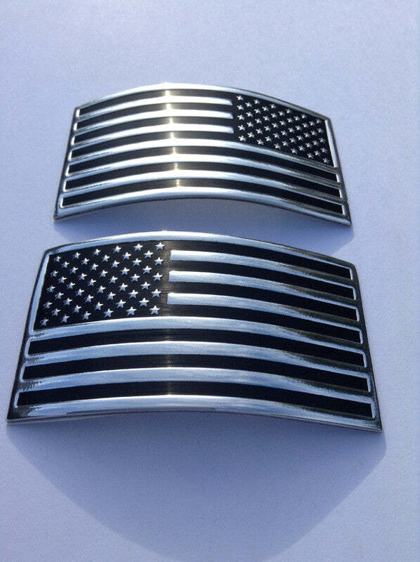 Two curved American flag emblem badges with a black and silver finish, displayed on a light gray background.